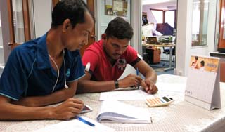 Two workers from GEC Construction at our office, calculating how much they're owed.